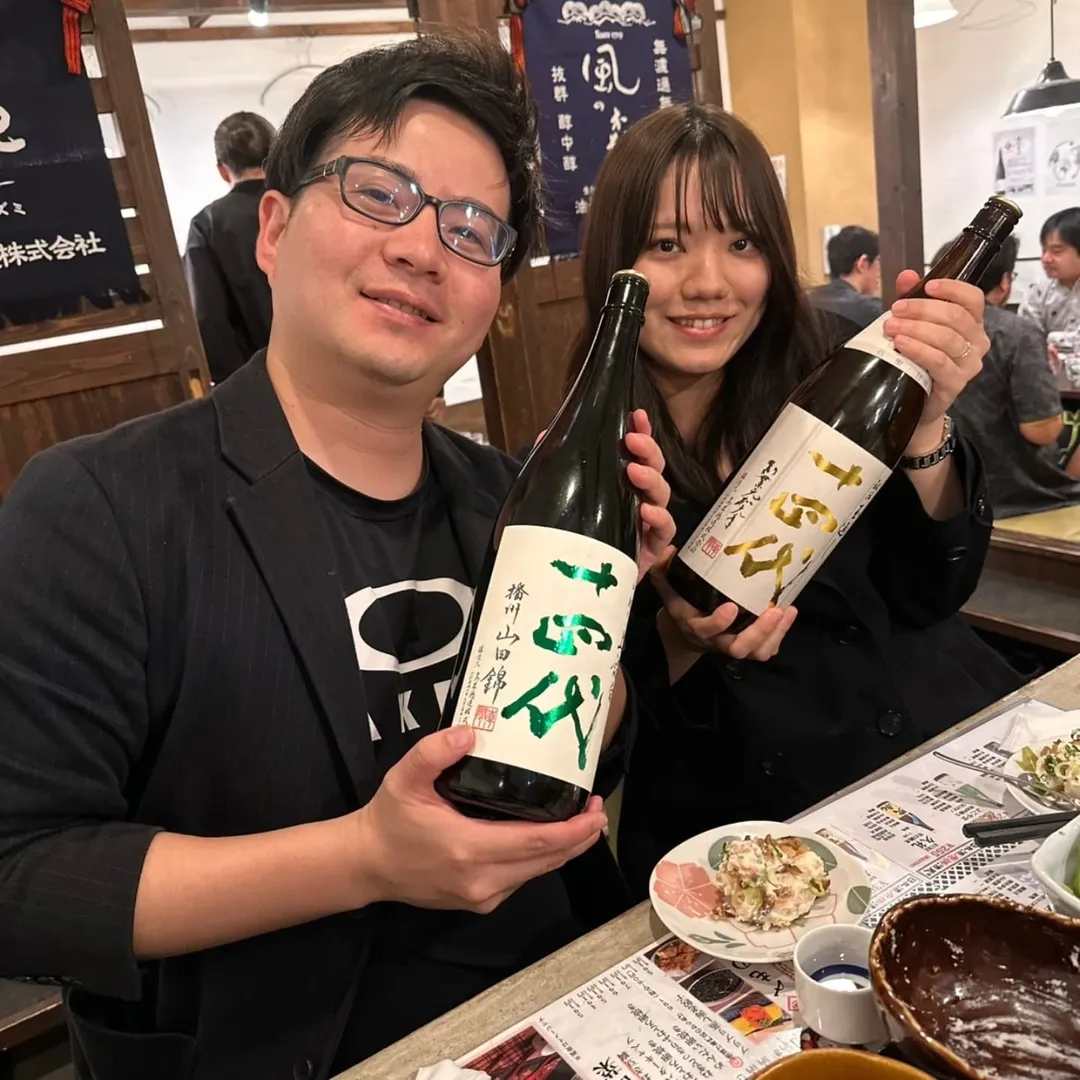 笑顔で日本酒のボトルを持つ様子